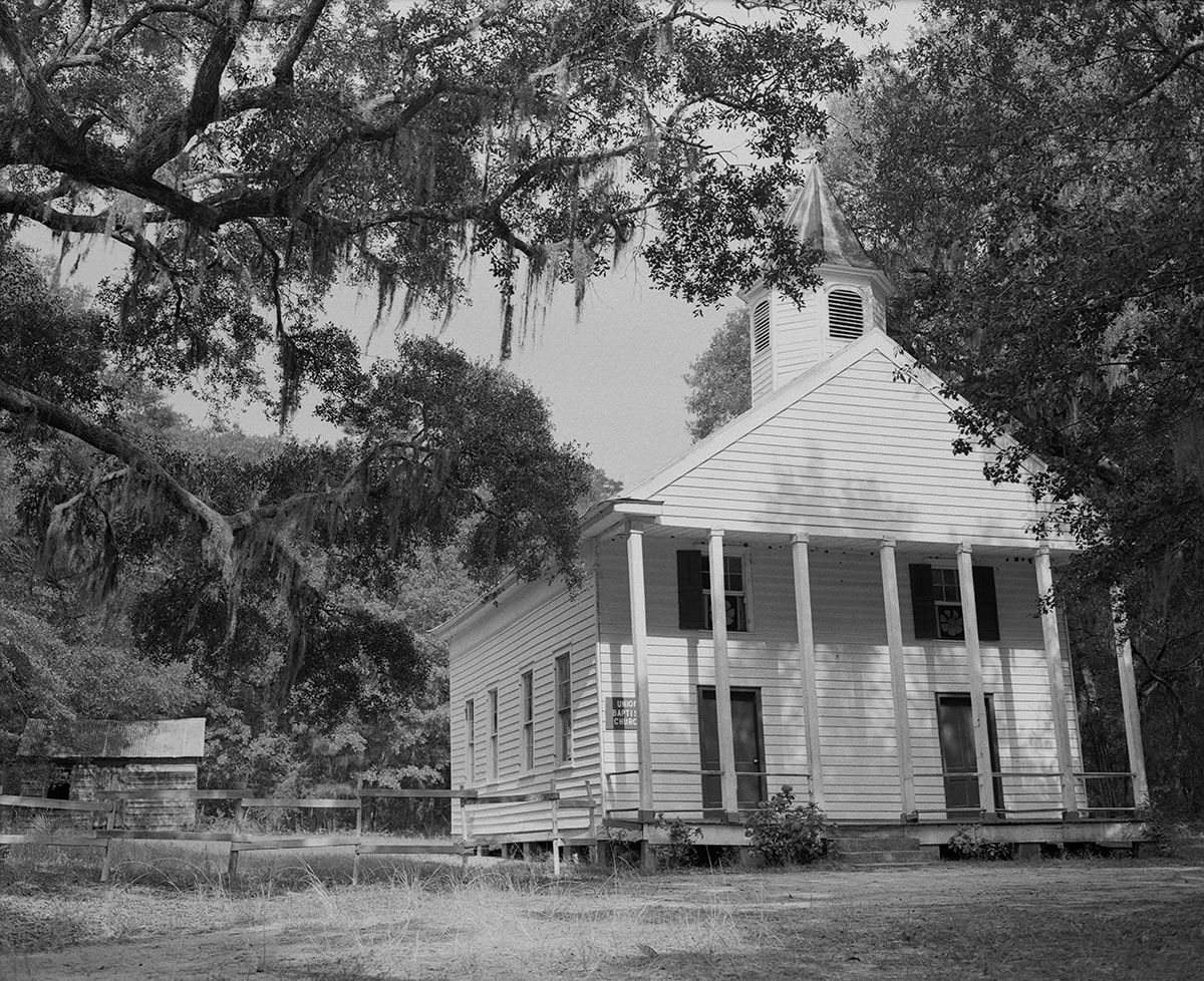 Black and white iamge of white church and trees